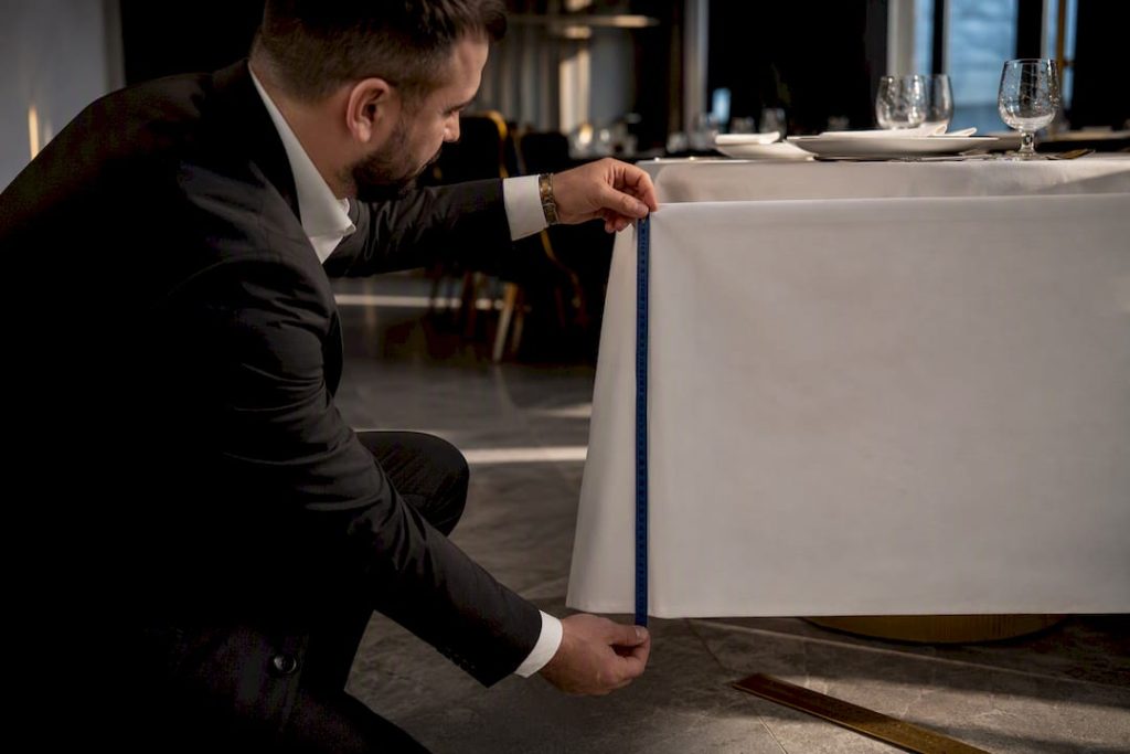 Hands measuring tablecloth drop at banquet table